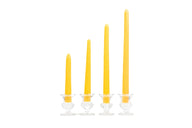 Four yellow taper candles stand in graduated heights within small, clear glass candle holders.
