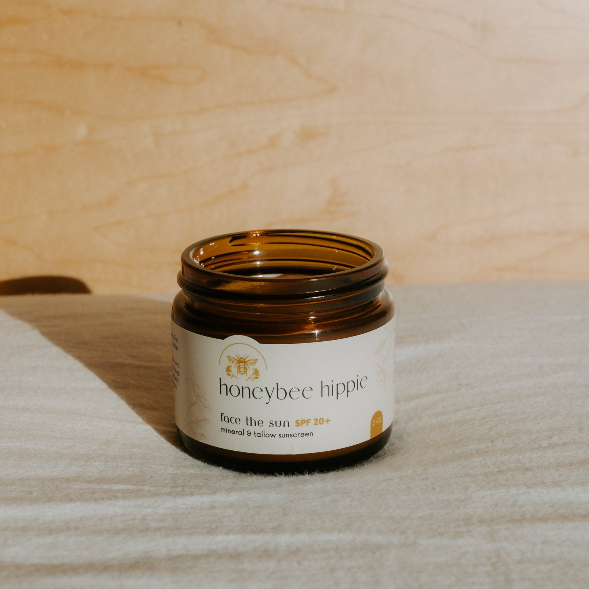 Jar of honeybee hippie sunscreen on a wooden surface