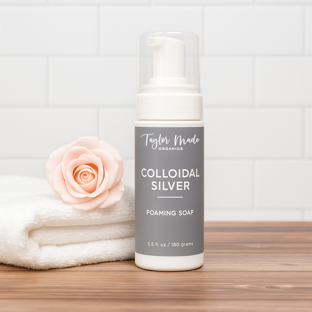 Bottle of colloidal silver foaming soap with a rose on a wooden surface