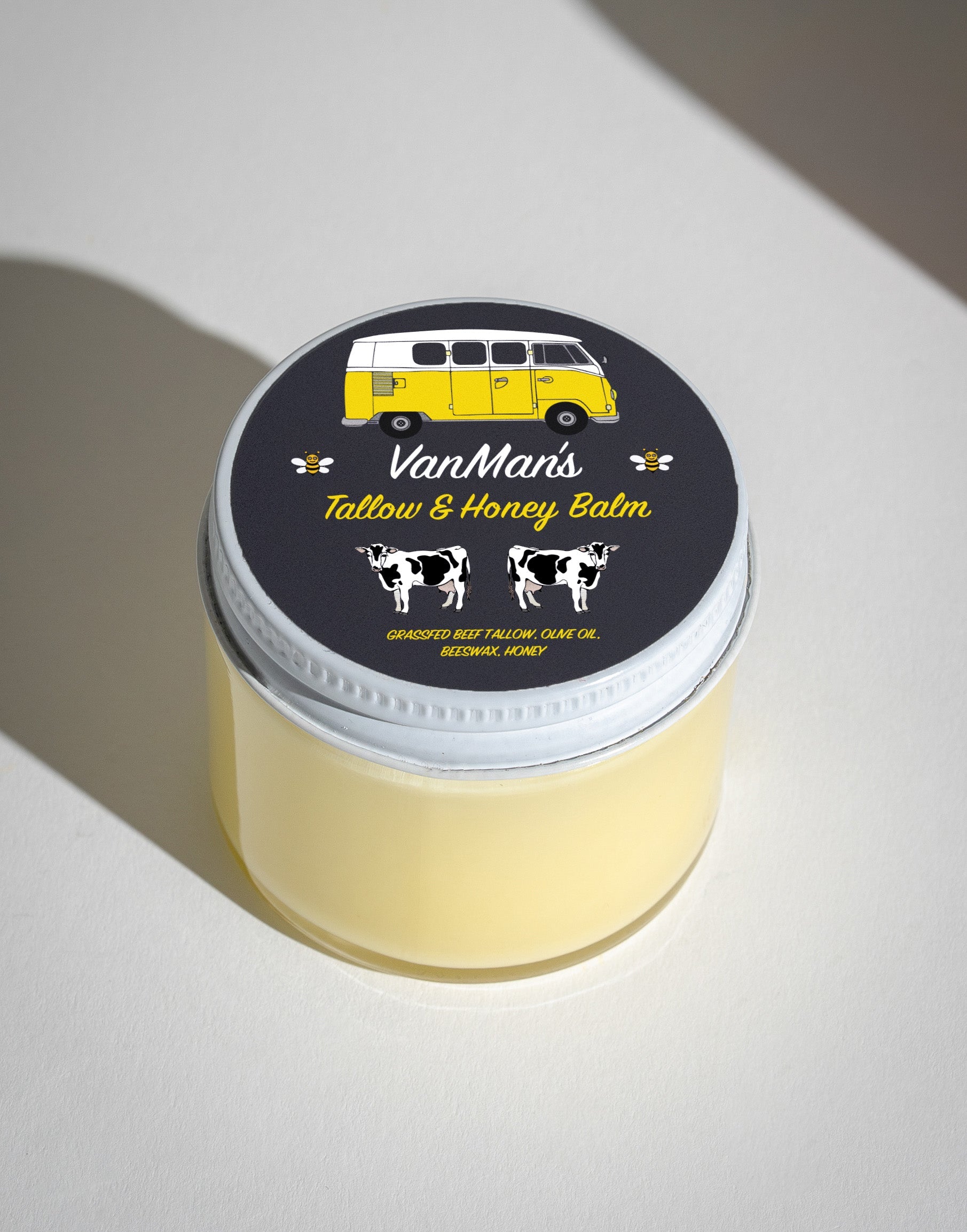 Showcases VanMan's Tallow & Honey Balm in a jar, featuring a retro van and cow illustrations on its label.
