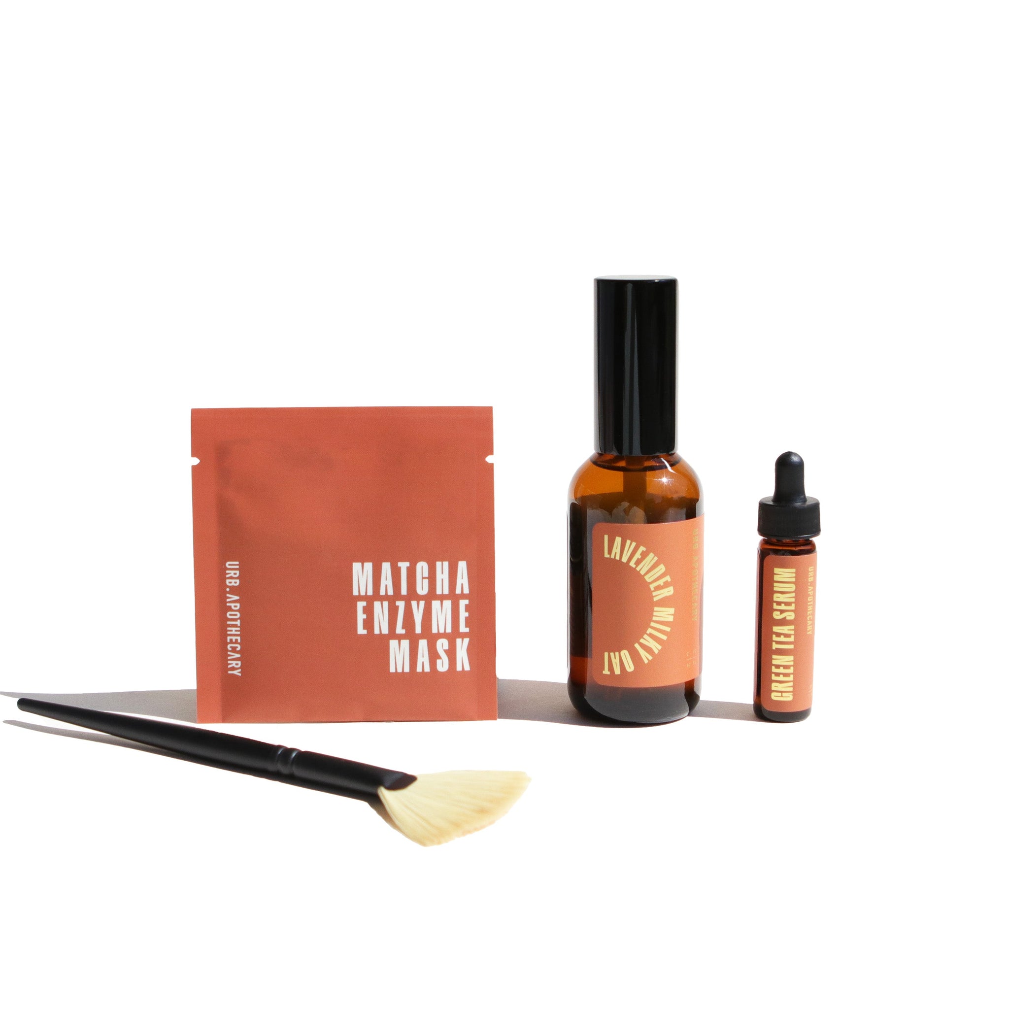 Urb Apothecary presents a skincare set featuring a matcha enzyme mask, lavender milky oat serum, green tea serum, and application brush for a complete facial treatment.

