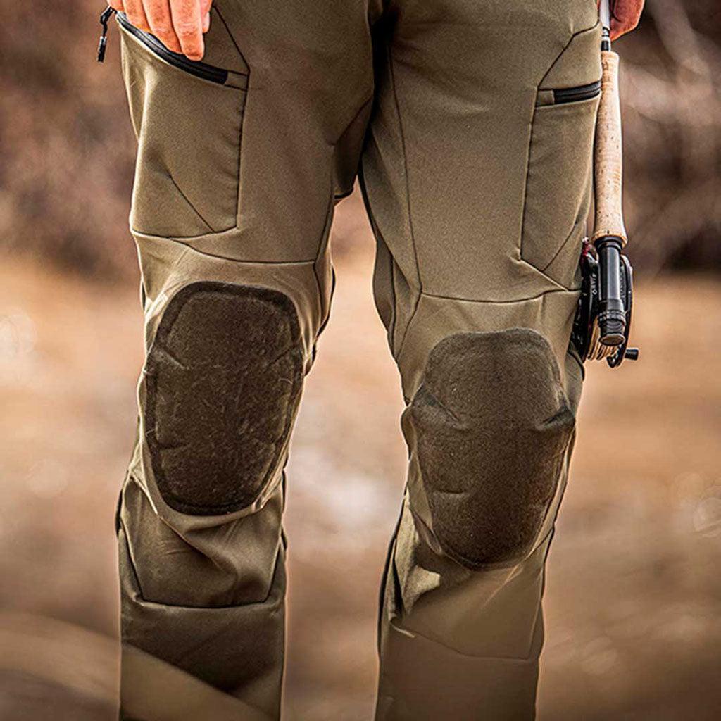 Person wearing brown tactical pants with knee pads, holding a fishing rod.