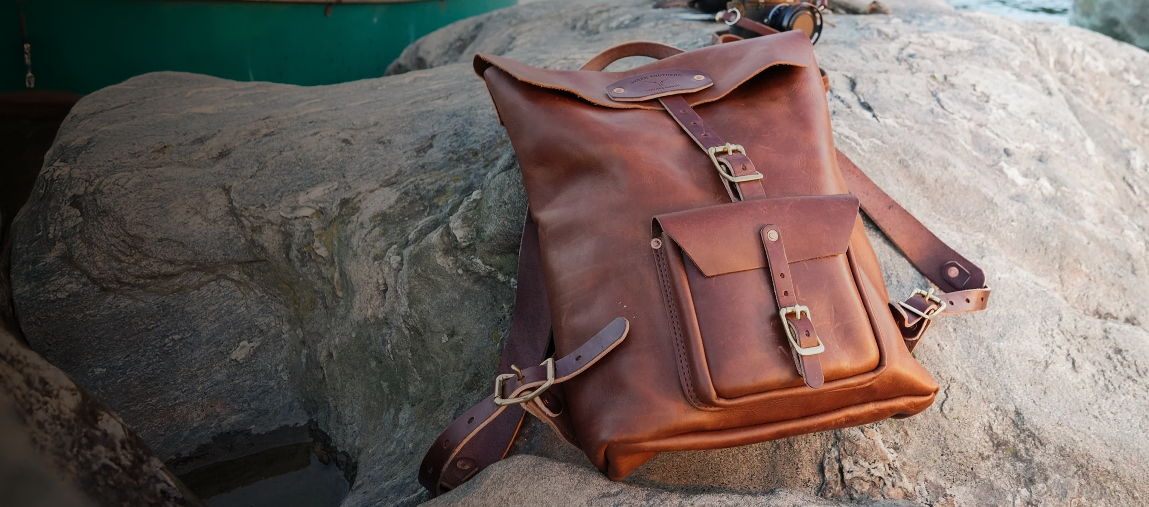 Brown handmade leather backpack by Urban Southern on a rock