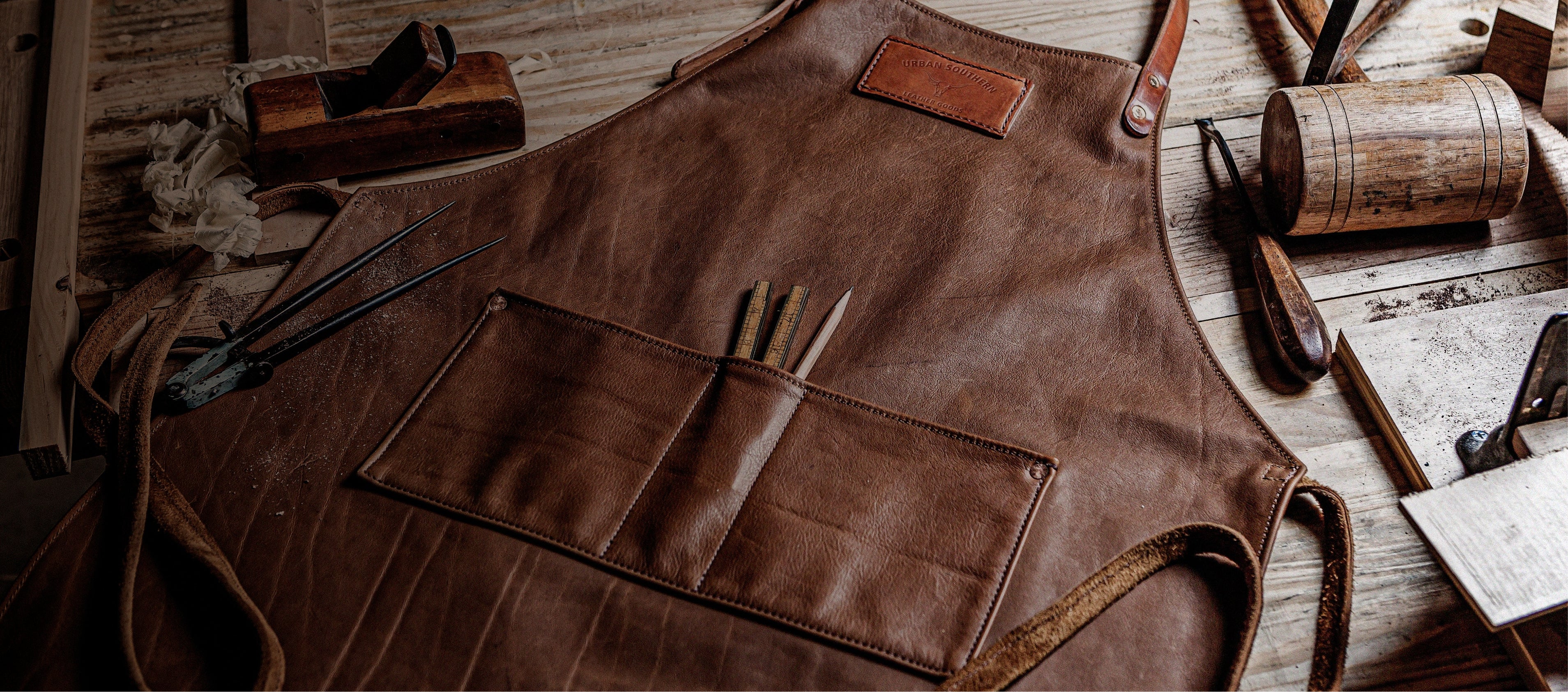 Brown leather apron with tools on a wooden surface