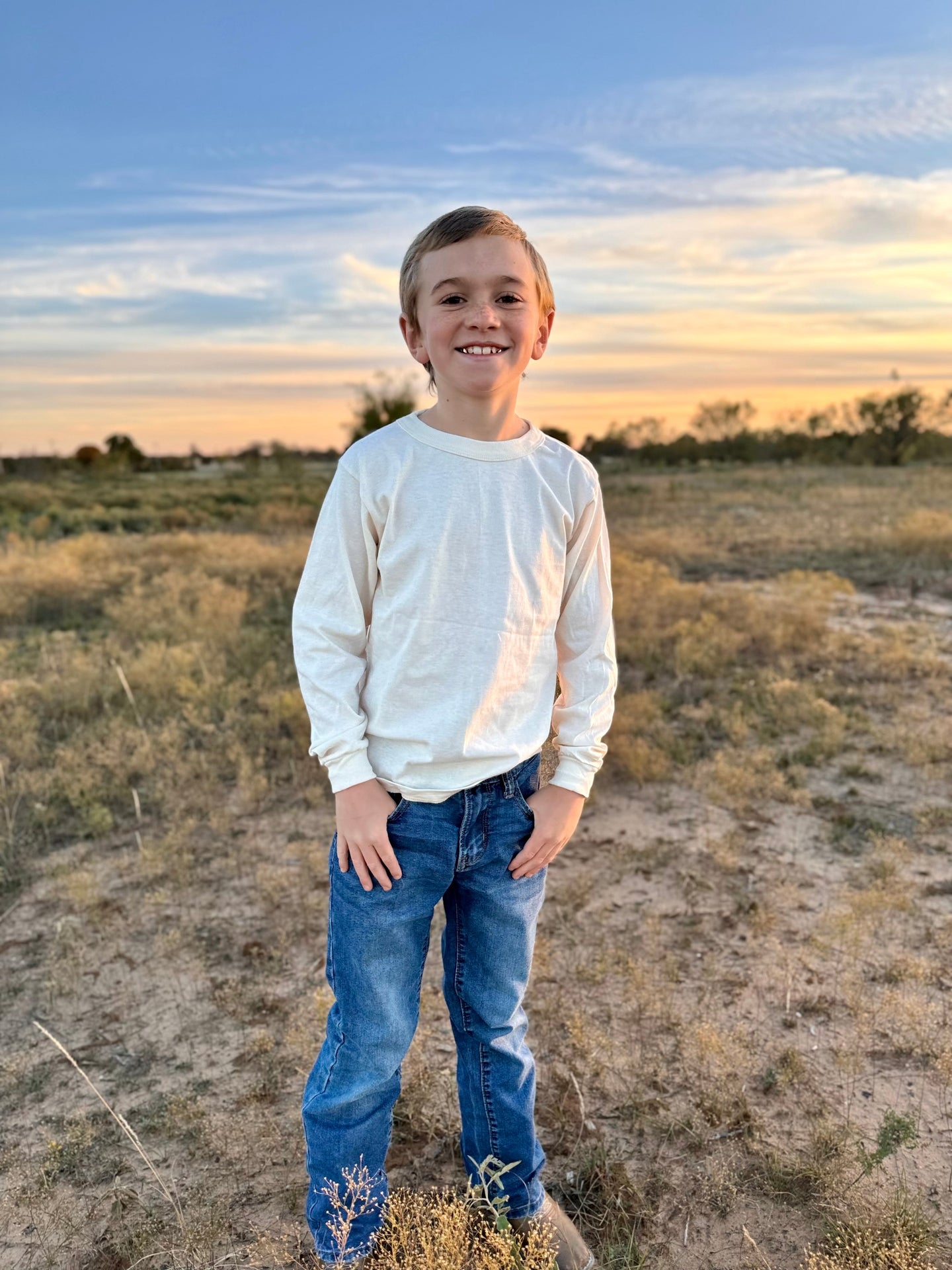 Child standing in a field with a sunset in the background wearing a Rowe Naturals Long Sleeve T Shirt