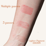 A person's arm displays swatches of a lighter pigment cosmetic product with varying coverage, showing multiple passes, three passes, and a lighter pigment.
