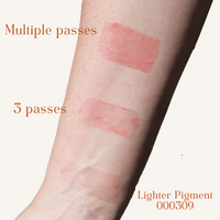 A person's arm displays swatches of a lighter pigment cosmetic product with varying coverage, showing multiple passes, three passes, and a lighter pigment.
