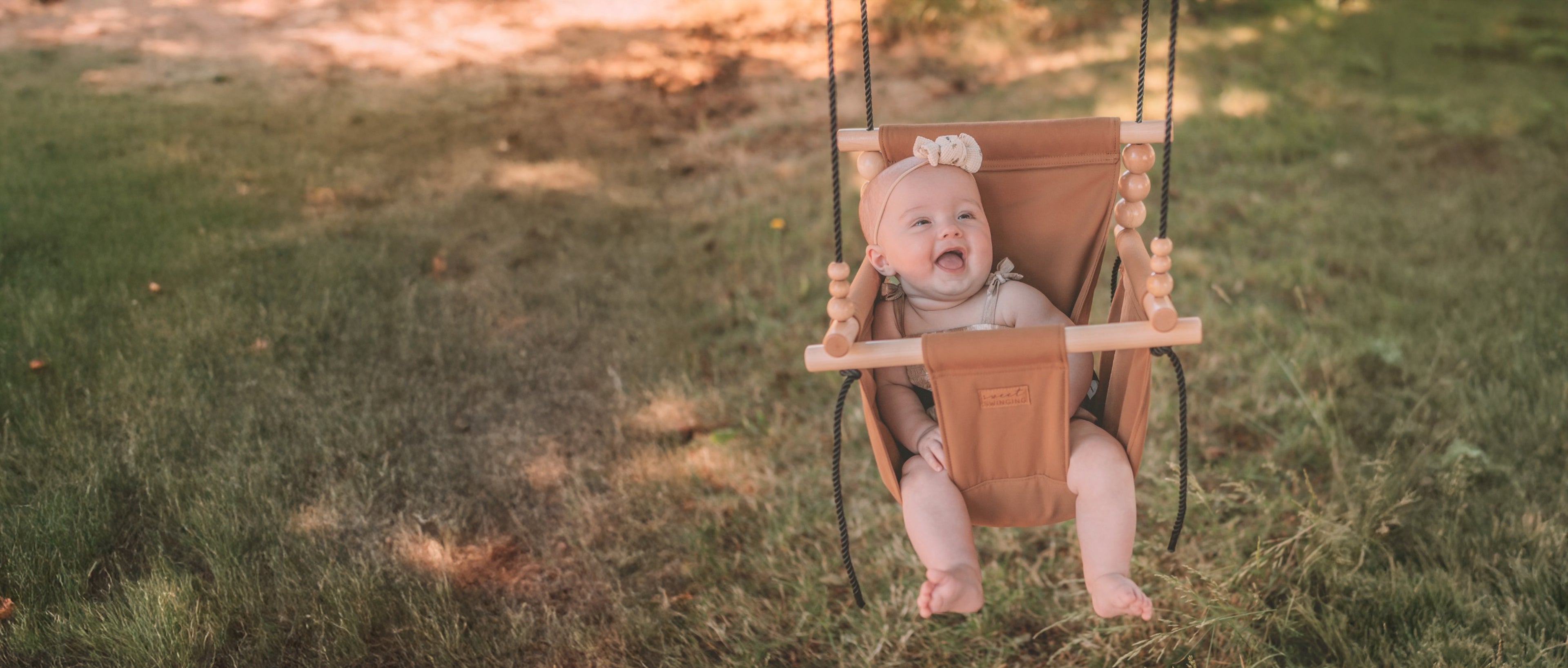 Baby in a swing on a grassy field