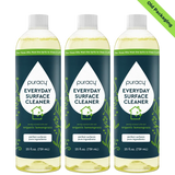 Three bottles of Puracy Everyday Surface Cleaner, featuring organic lemongrass scent and old packaging, are shown.
