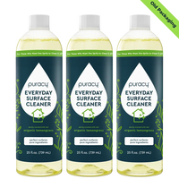 Three bottles of Puracy Everyday Surface Cleaner, featuring organic lemongrass scent and old packaging, are shown.
