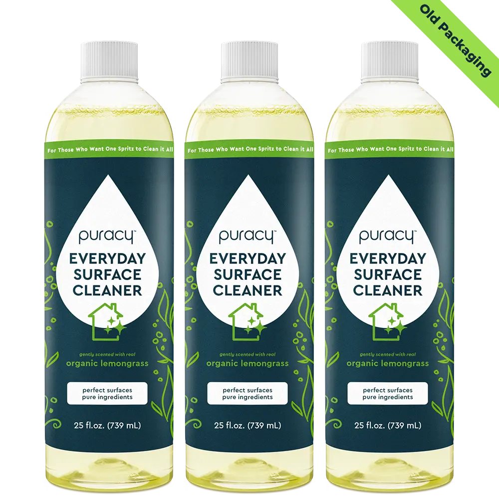 Three bottles of Puracy Everyday Surface Cleaner, featuring organic lemongrass scent and old packaging, are shown.
