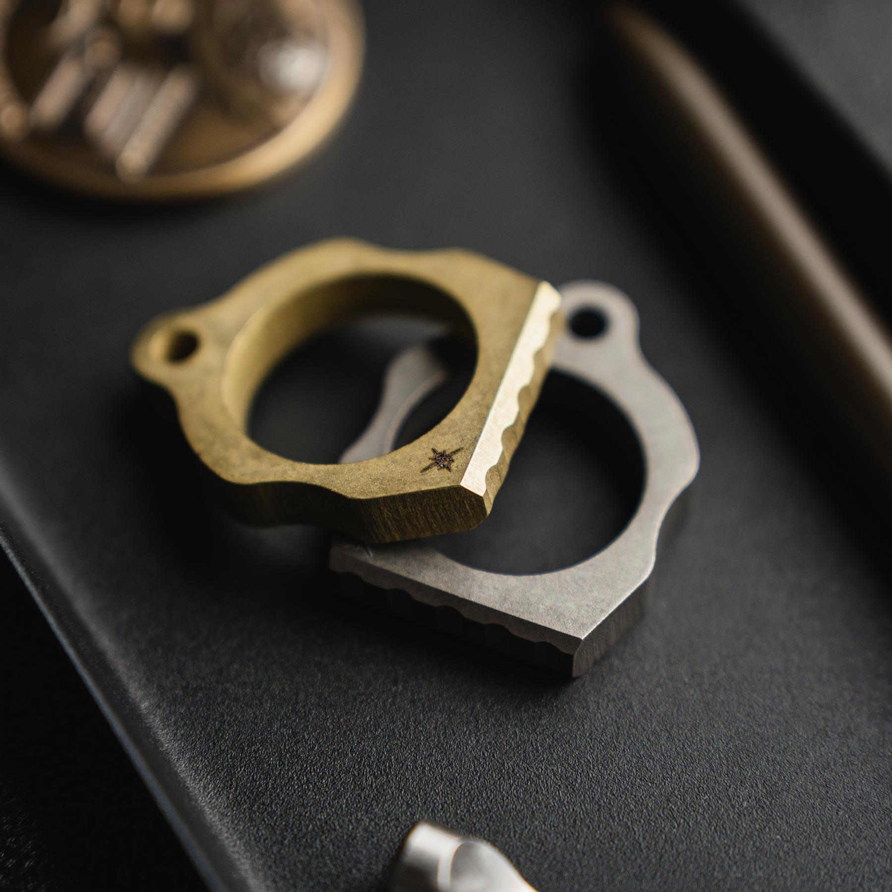 Two thumper tools, one gold and one silver, on a dark surface.