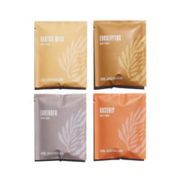 Four Urb.Apothecary bath soak packets, featuring cactus milk, eucalyptus, lavender, and rosehip scents, sit arranged on a white surface.
