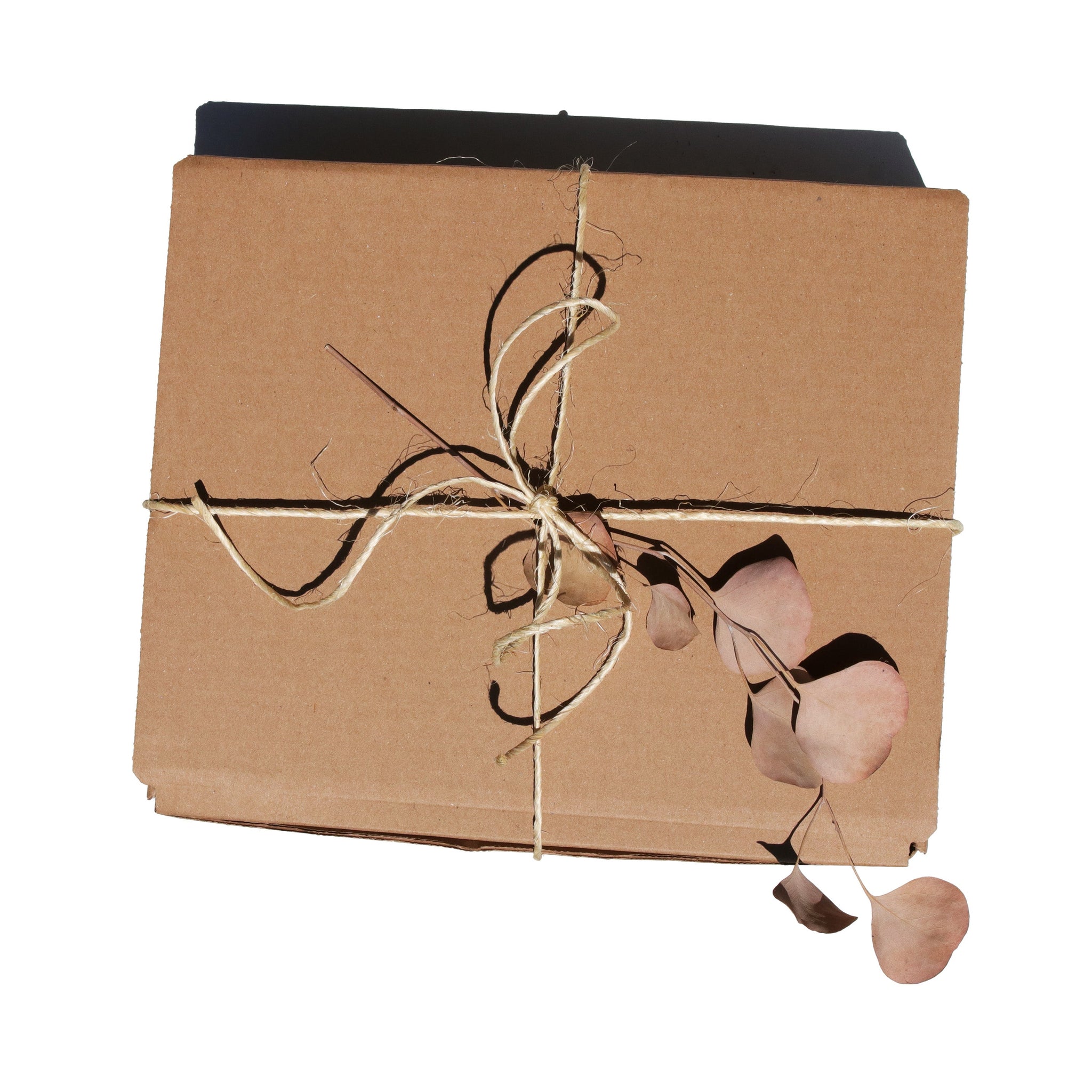 A brown cardboard gift box receives a rustic touch with twine and dried eucalyptus leaves.
