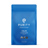 Showcases a blue bag of Purity Coffee Calm, a decaffeinated and consciously crafted ground coffee for serenity.
