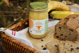 Jar of 'Spring Sunrise' brown butter ghee with bread and bananas on a wooden surface