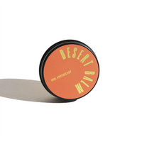 URB Apothecary Desert Balm rests on a white surface, casting a soft shadow.
