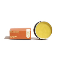 Urb Apothecary Desert Balm in a tin sits beside its cardboard packaging.

