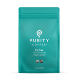 Purity Coffee's teal bag showcases their "Flow" medium roast ground coffee, emphasizing organic and bird-friendly sourcing.
