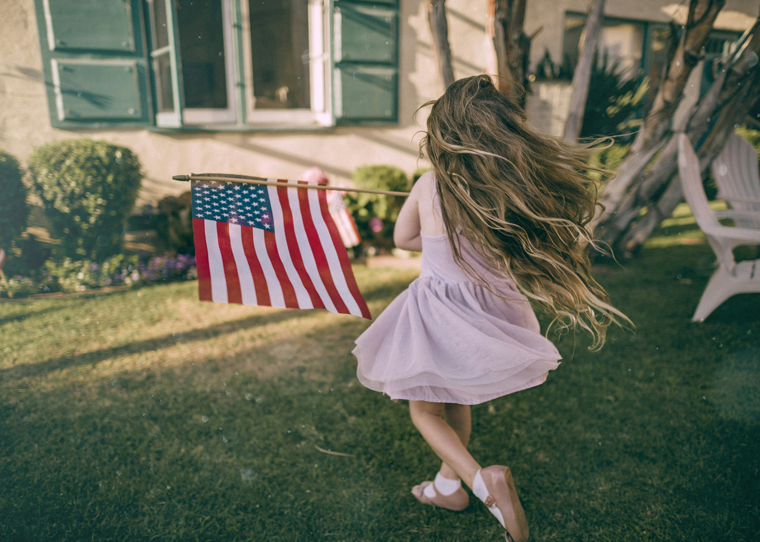 Little girl in a garden holding an American flag