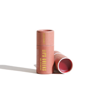 Two tubes of URB Apothecary Lips Cheeks natural beeswax lip tint sit against a stark white background.
