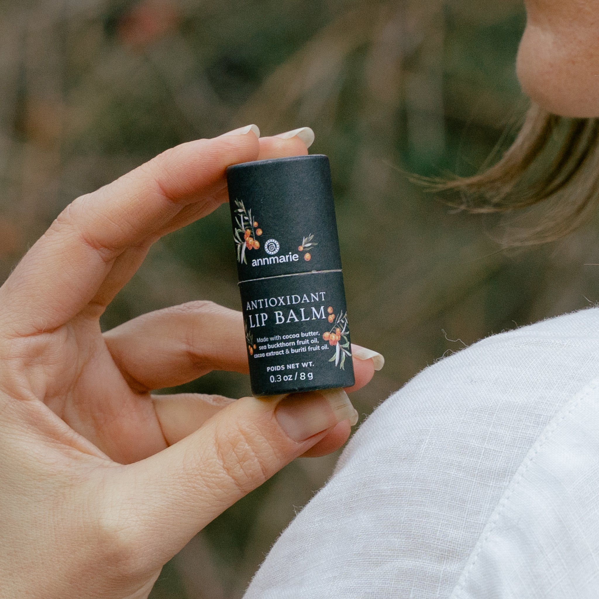 A woman holds Annmarie Antioxidant Lip Balm made with cocoa butter and sea buckthorn fruit oil.

