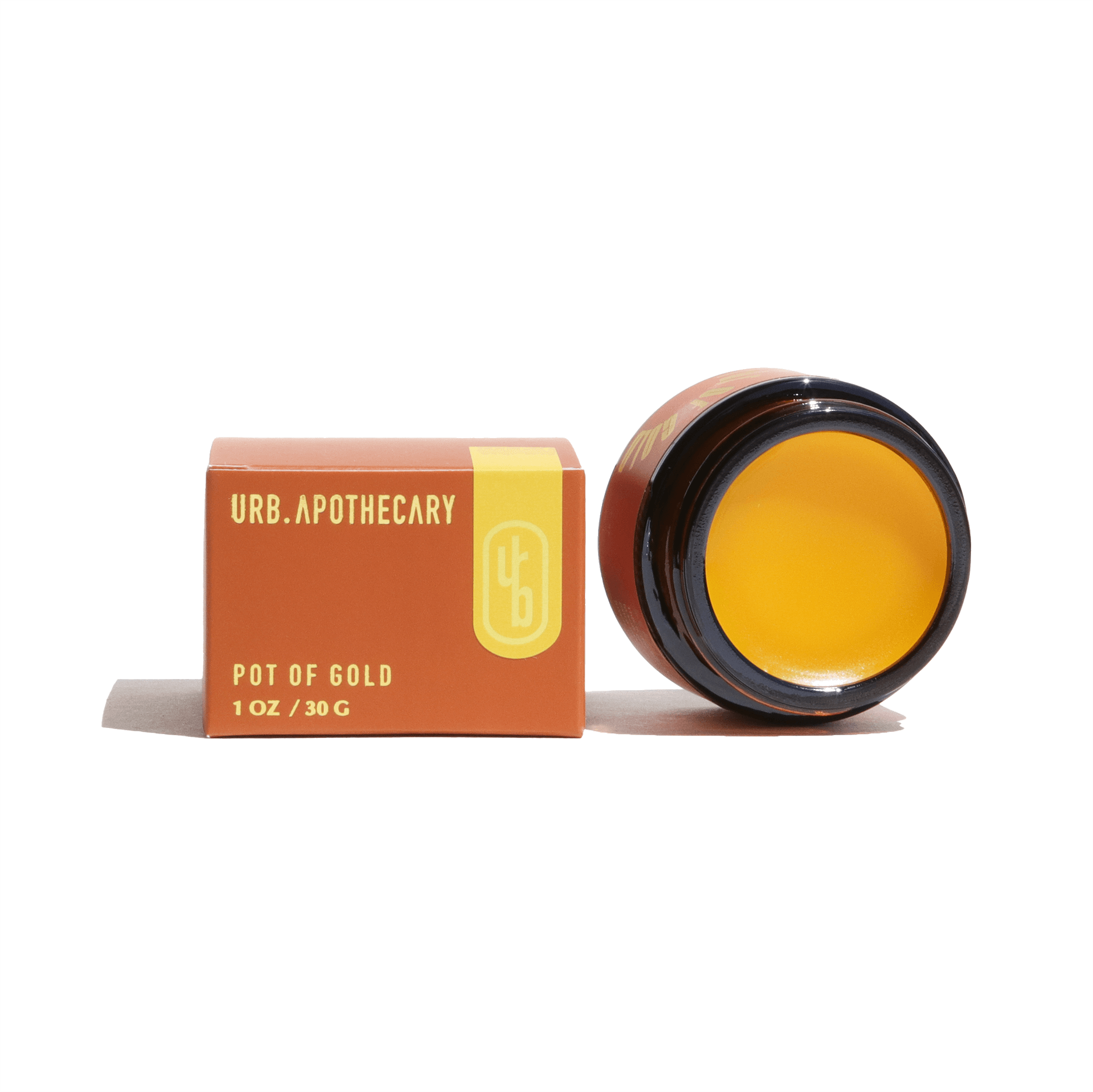 URB Apothecary's Pot of Gold balm sits beside its box, showcasing natural skincare.
