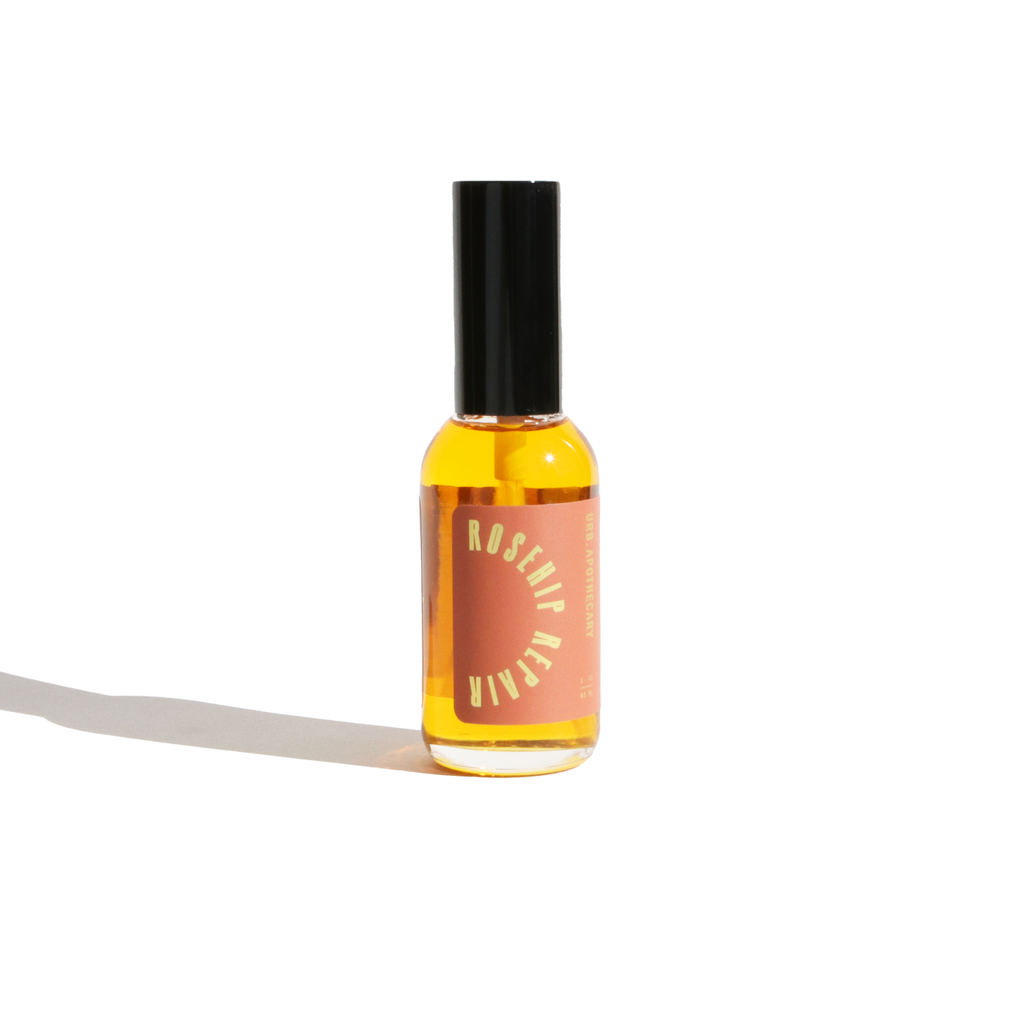 A bottle of Urb Apothecary Rosehip Repair facial oil sits on a white surface.
