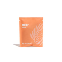 Showcases a vibrant orange packet of URB. Apothecary Rosehip bath soak.
