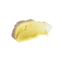 Close-up shows a smear of yellow, shimmering skincare balm against a bright white background.

