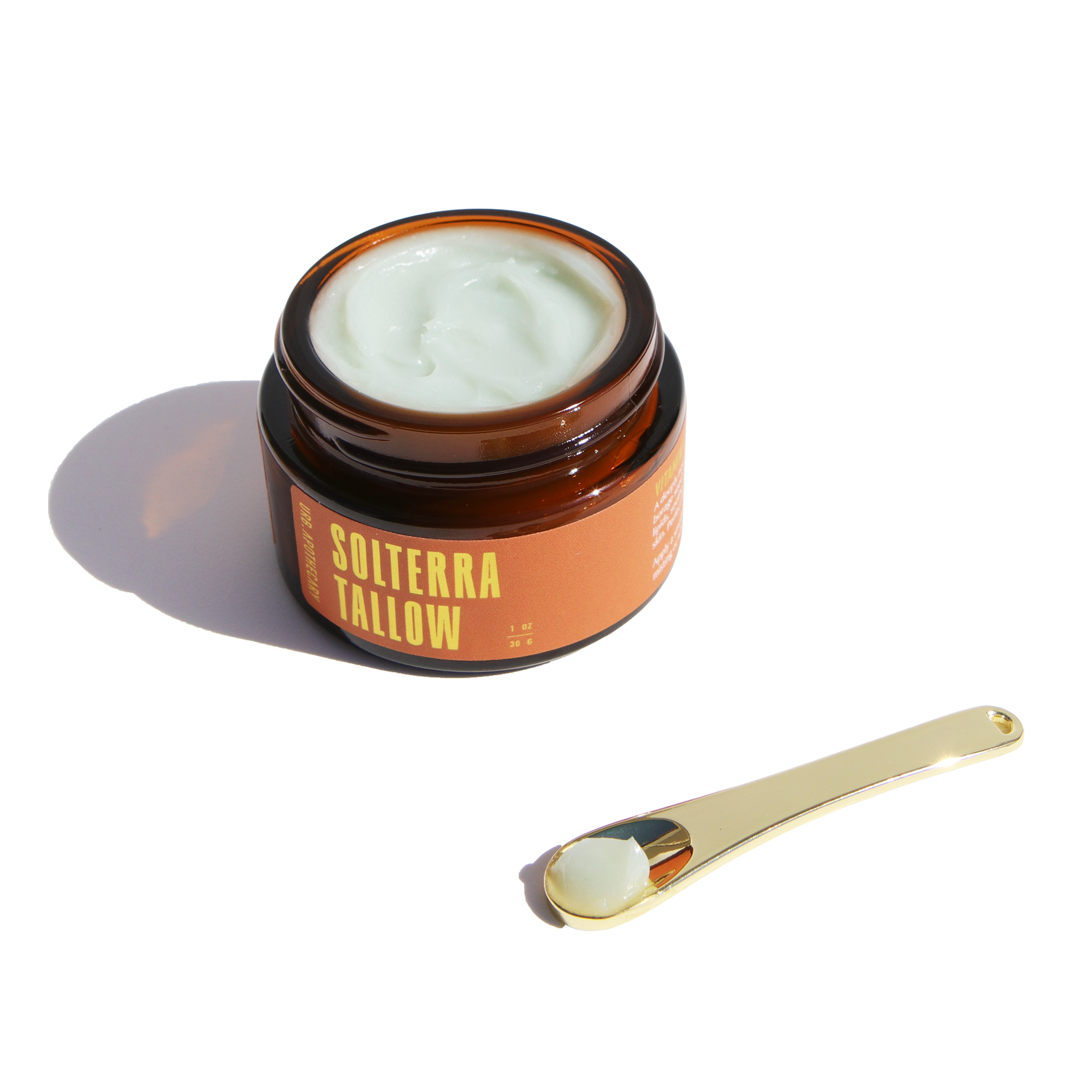 Showcases Solterra Tallow moisturizer in a brown glass jar with a gold applicator spoon holding the product.
