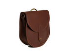 A brown leather saddle bag with brass hardware displays against a white background.
