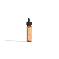 Jasmine Mandarin aromatherapy oil in a small bottle with a dropper cap sits on a white surface.
