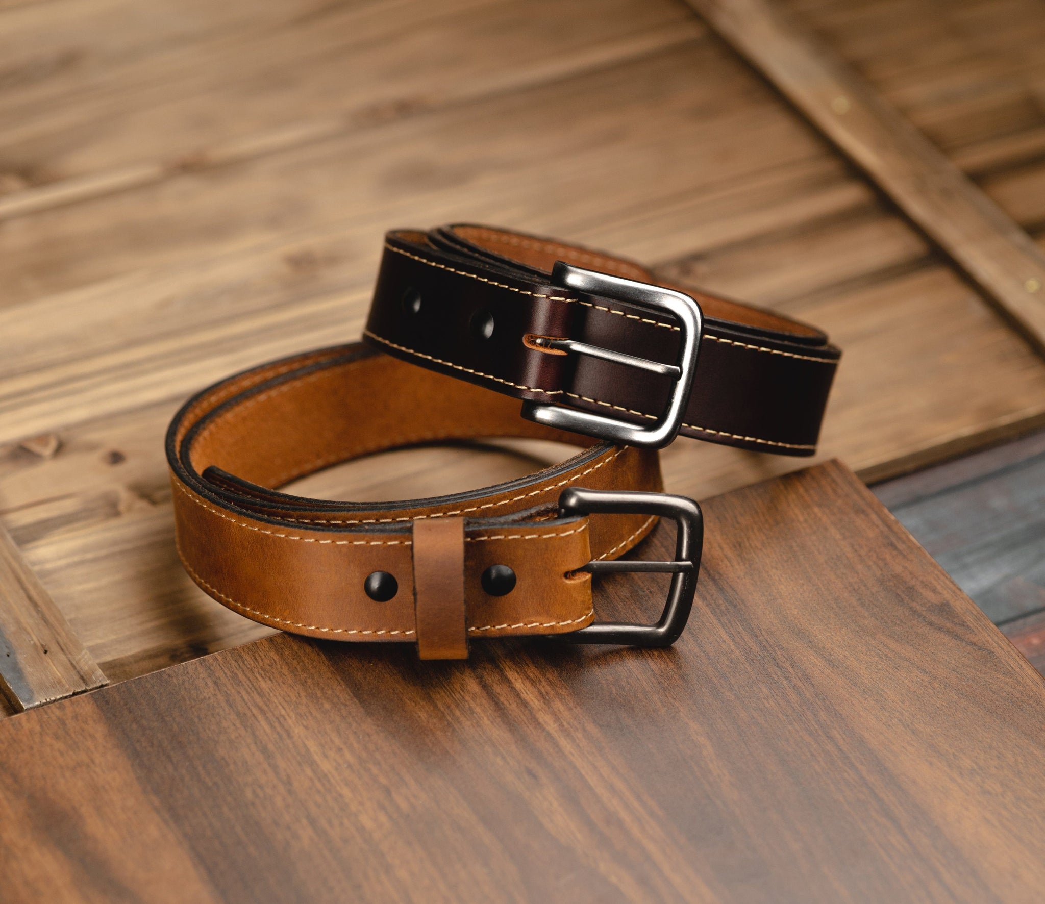Brown leather belt with silver buckles on a wooden surface