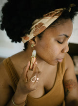 Woman applies "Slumber Serum" aromatherapy roll-on to her neck for relaxation.
