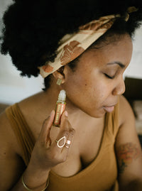 Woman applies "Slumber Serum" aromatherapy roll-on to her neck for relaxation.
