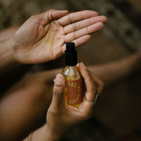 Woman holds bottle of Rosani Repair face oil, preparing to apply it to her hand.
