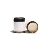 Two elegant "Smoked Santal" scented candles, one standing and one lying down, are displayed against a clean white background.
